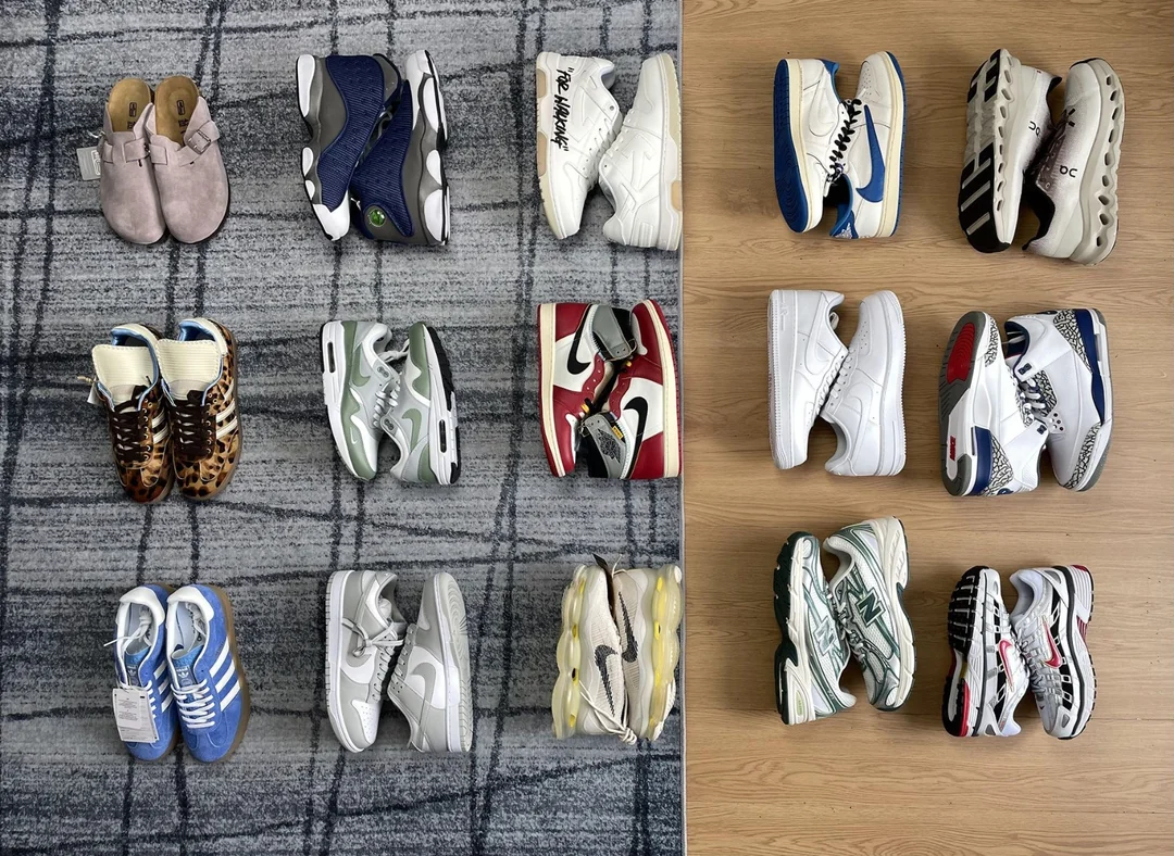 Twelve pairs of sneakers and shoes are neatly arranged in a grid on a checkered carpet and wooden floor, featuring various styles, colors, and brands.