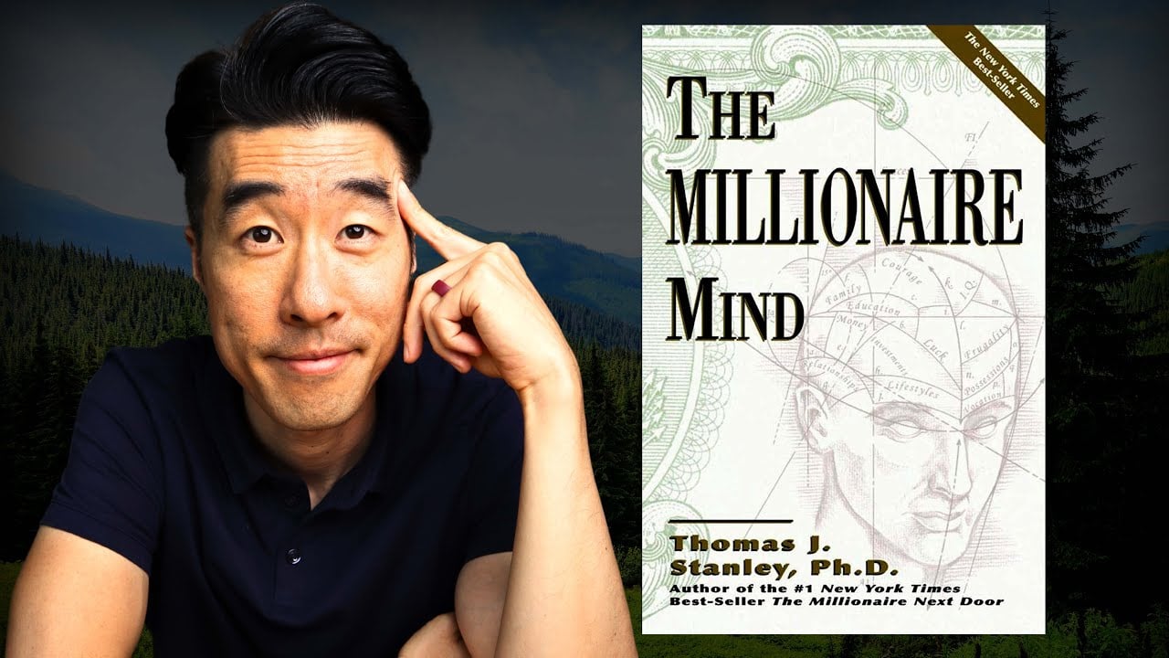 A smiling man in a dark shirt sits with his hand on his cheek next to the book cover of "The Millionaire Mind" by Thomas J. Stanley, against a blurred background of trees and mountains.