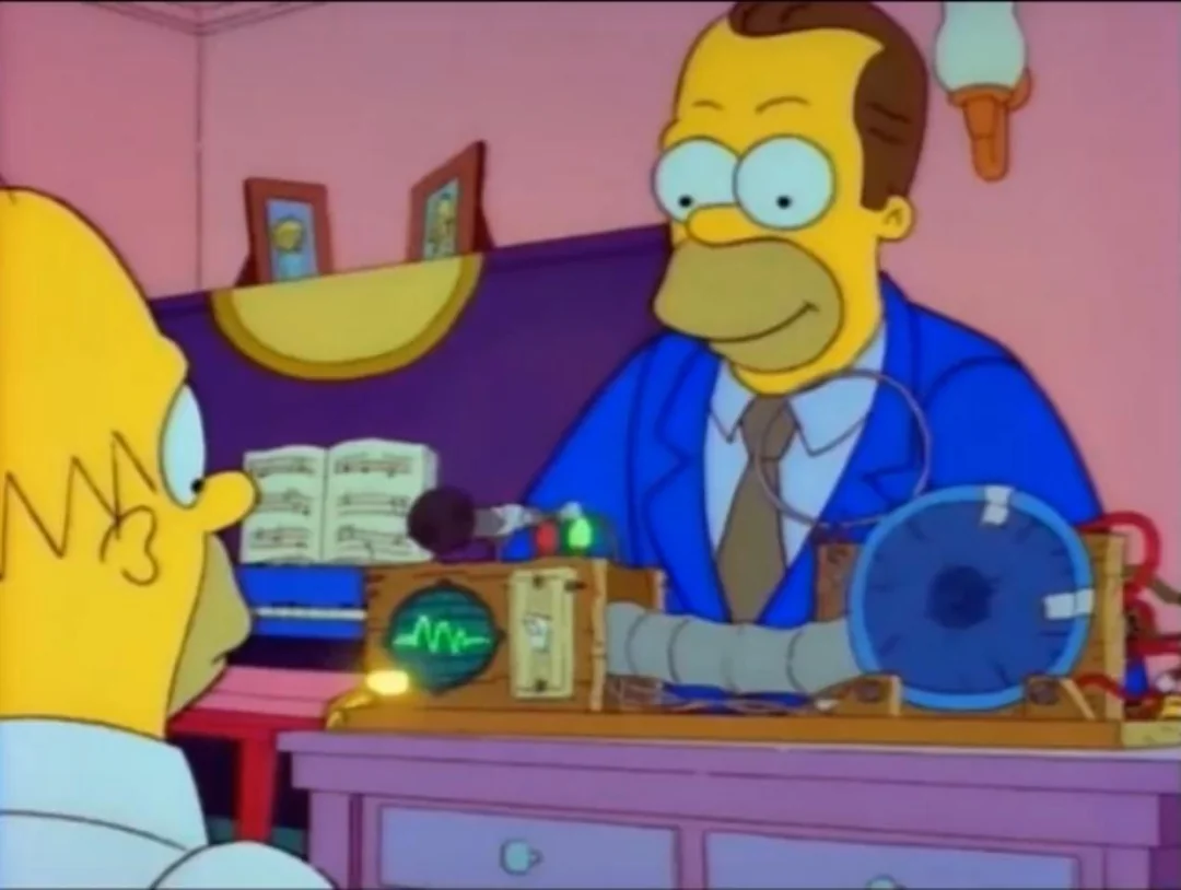 A cartoon man in a blue suit operates a strange machine with wires and dials, facing another character with a similar appearance in a pink-walled room with a bookshelf and lamp.