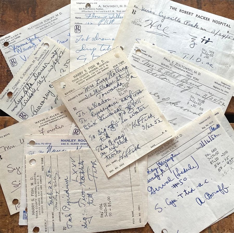 A scattered pile of handwritten vintage doctor’s prescription notes and medical forms, some with signatures and medical abbreviations, on a wooden surface. The notes appear aged and contain various doctors’ letterheads.