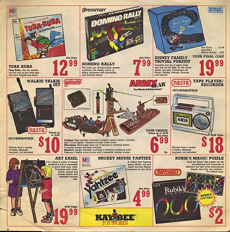 Vintage toy store ad featuring board games, a domino rally set, a Trivial Pursuit game, walkie talkies, a tape recorder, art easel, Rubik's Magic puzzle, and prices, with Kay-Bee Toy Stores logo at the bottom.