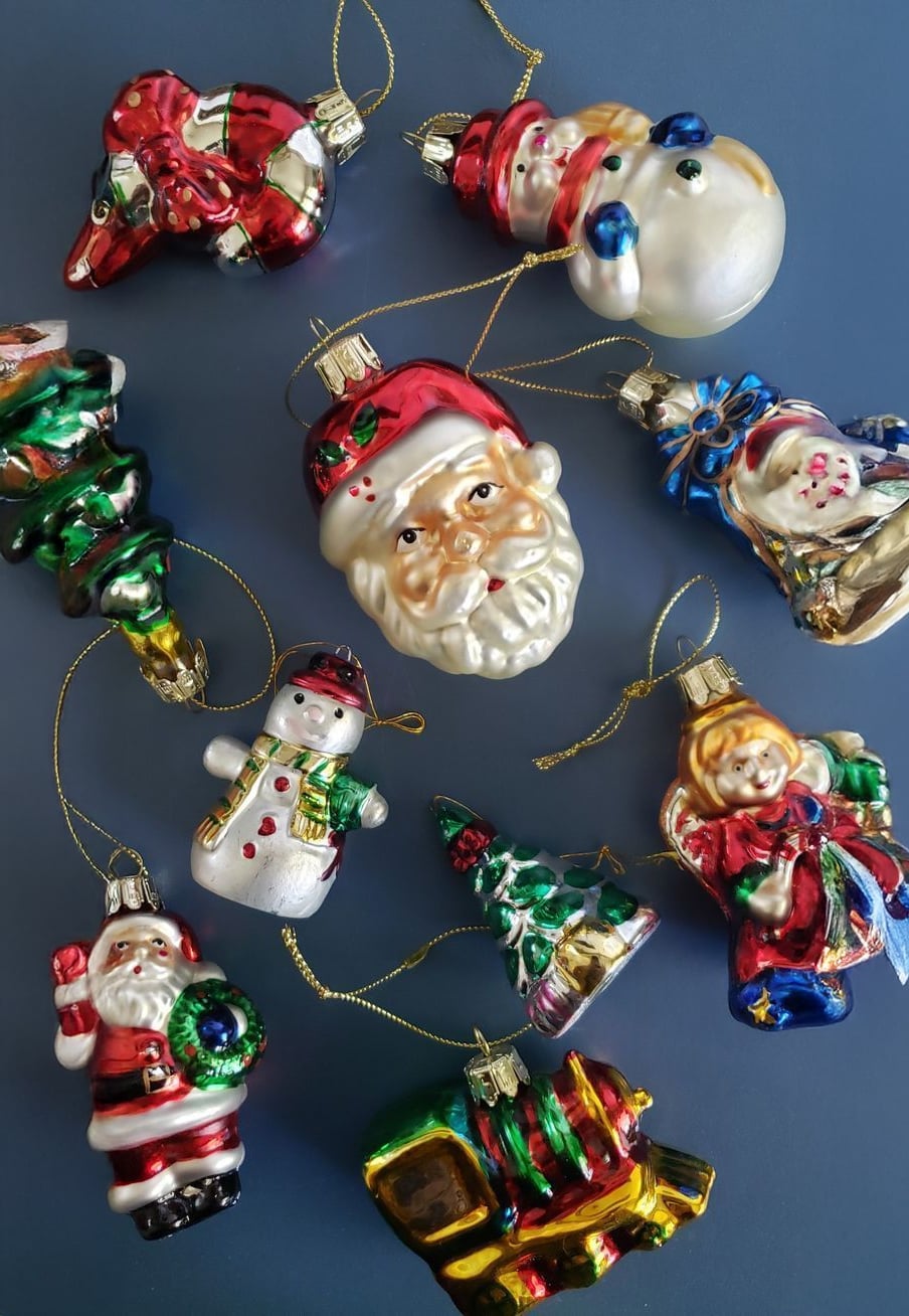 A collection of colorful Christmas ornaments, including Santa Claus, a snowman, a Christmas tree, a train, and other festive shapes, arranged on a blue background.