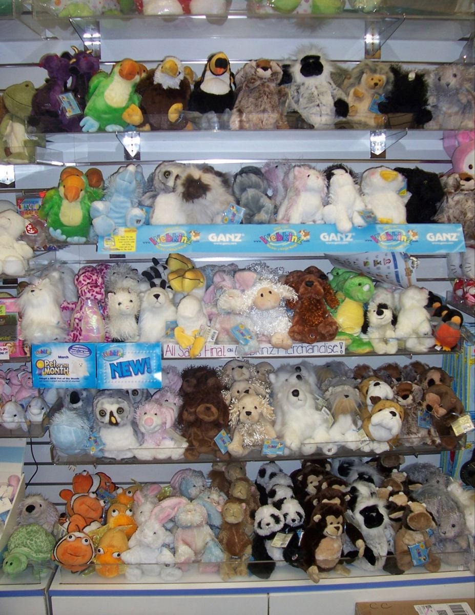 Shelves filled with a variety of plush stuffed animals, including bears, pandas, penguins, and other creatures, neatly arranged in a store display.