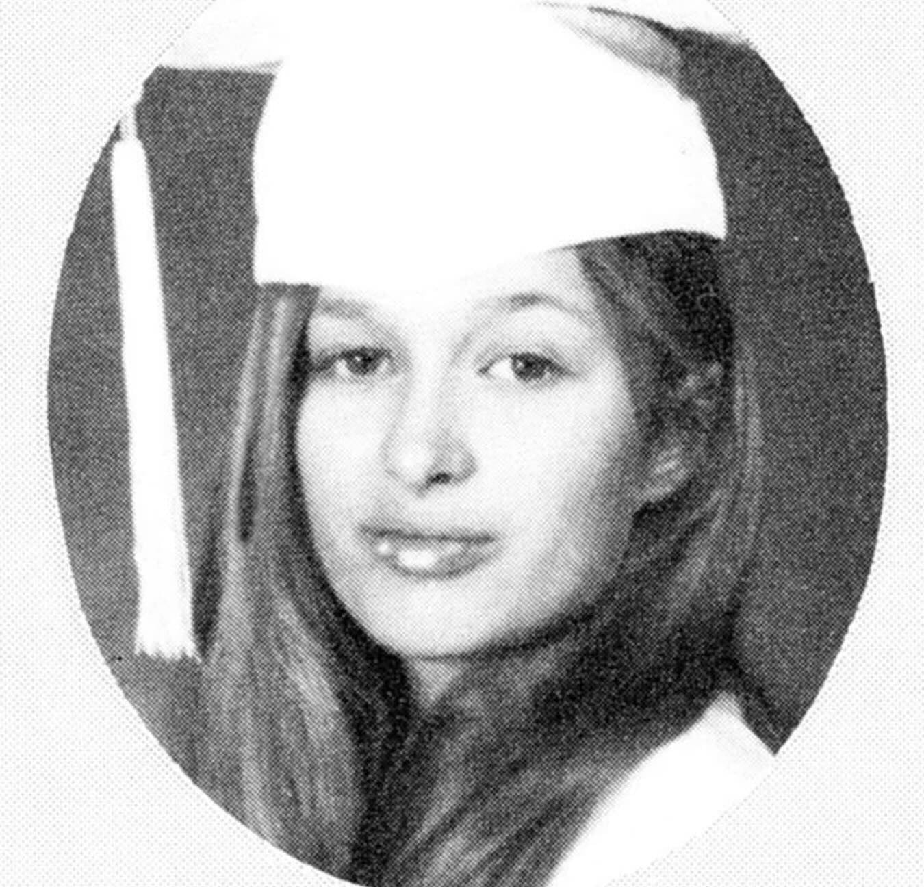 A young woman wearing a graduation cap and gown poses for a formal portrait, looking slightly past the camera with a neutral expression. The image is in black and white and has an oval vignette effect.
