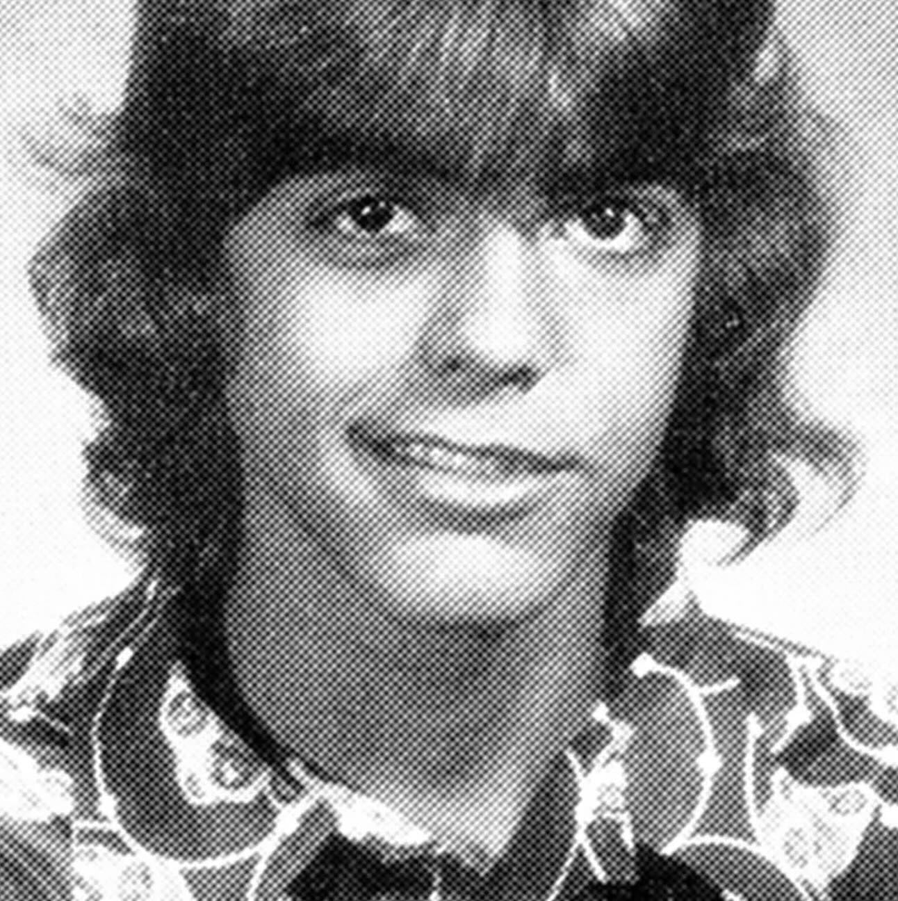 Black and white yearbook photo of a young person with medium-length, shaggy hair, wearing a patterned collared shirt and smiling slightly at the camera.