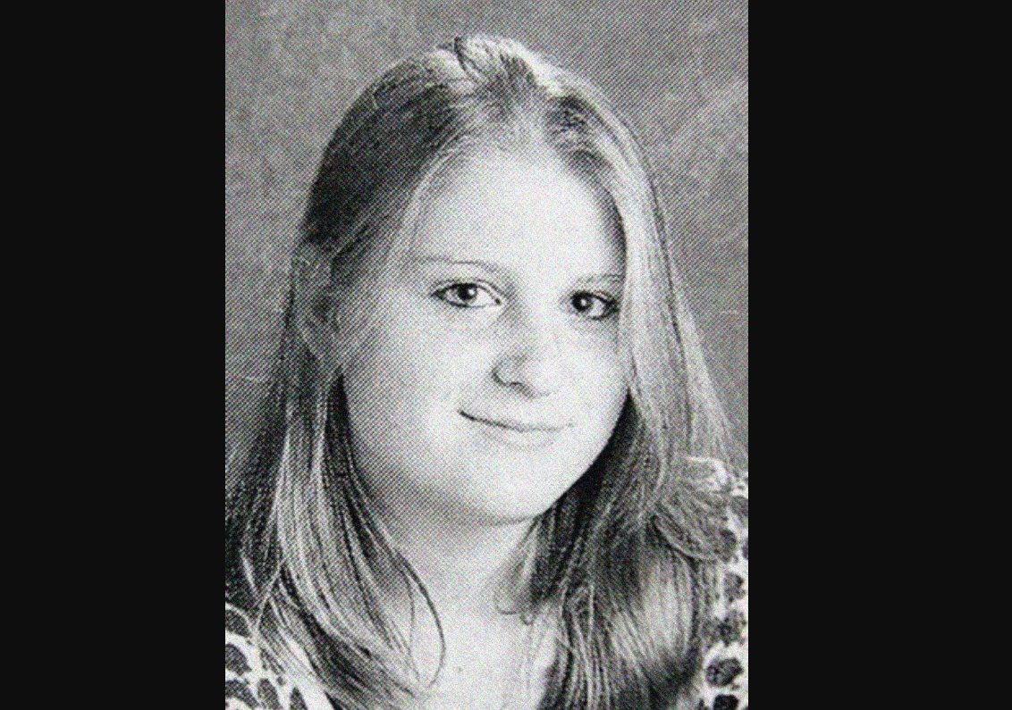 Black and white yearbook-style portrait of a young woman with straight, light-colored hair, parted slightly to the side, wearing a patterned top and looking at the camera with a neutral expression.