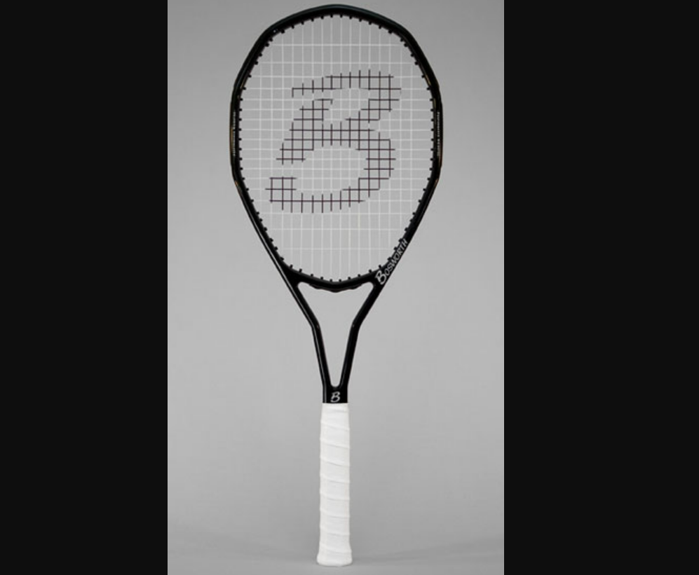 A black tennis racket with white strings and a large "B" on the strings, featuring a white grip, is shown standing vertically against a neutral gray background.