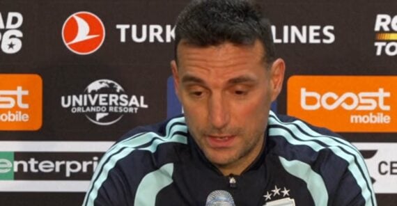 A man in a dark sports jacket speaks into a microphone at a press conference, with sponsor logos including Turkish Airlines and Universal Orlando Resort visible behind him.