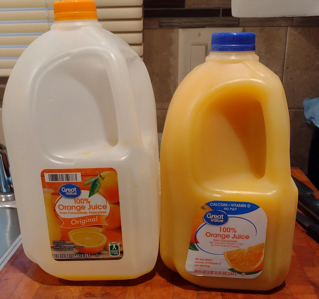 Two plastic jugs of Great Value 100% Orange Juice stand side by side on a counter. The left jug is labeled "Original," while the right jug is labeled "Calcium + Vitamin D." Both contain bright orange juice.