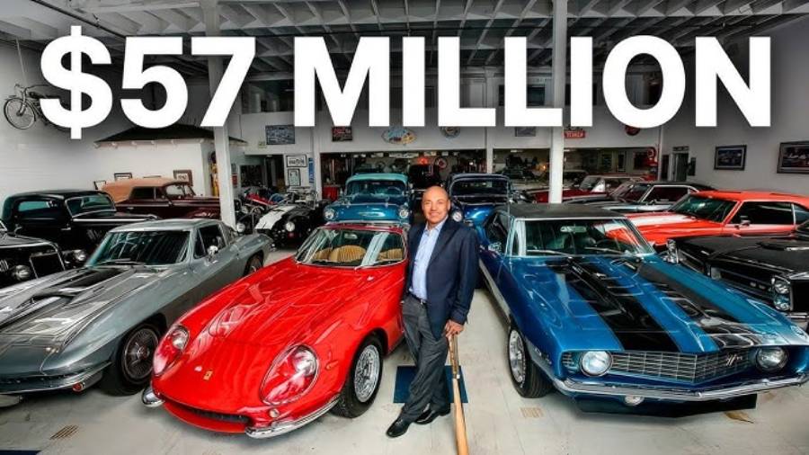 A man stands in a garage filled with classic cars, including a red Ferrari and a blue muscle car, holding a baseball bat. Large text above him reads "$57 MILLION.