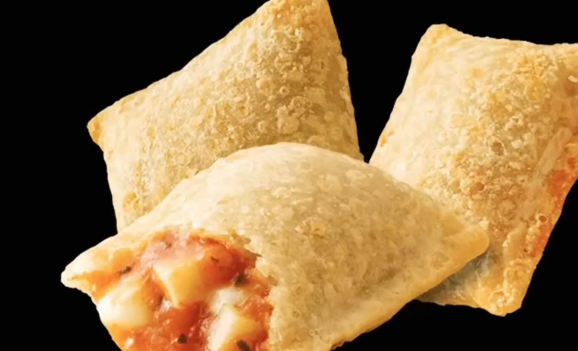 Three golden-brown, square pizza rolls are shown. One is split open, revealing melted cheese and tomato sauce inside. The background is black, making the rolls stand out.