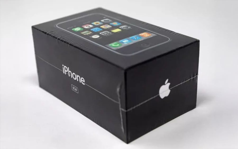 A sealed black box of the original iPhone, featuring the Apple logo, iPhone label, and an image of the device with app icons on its screen.