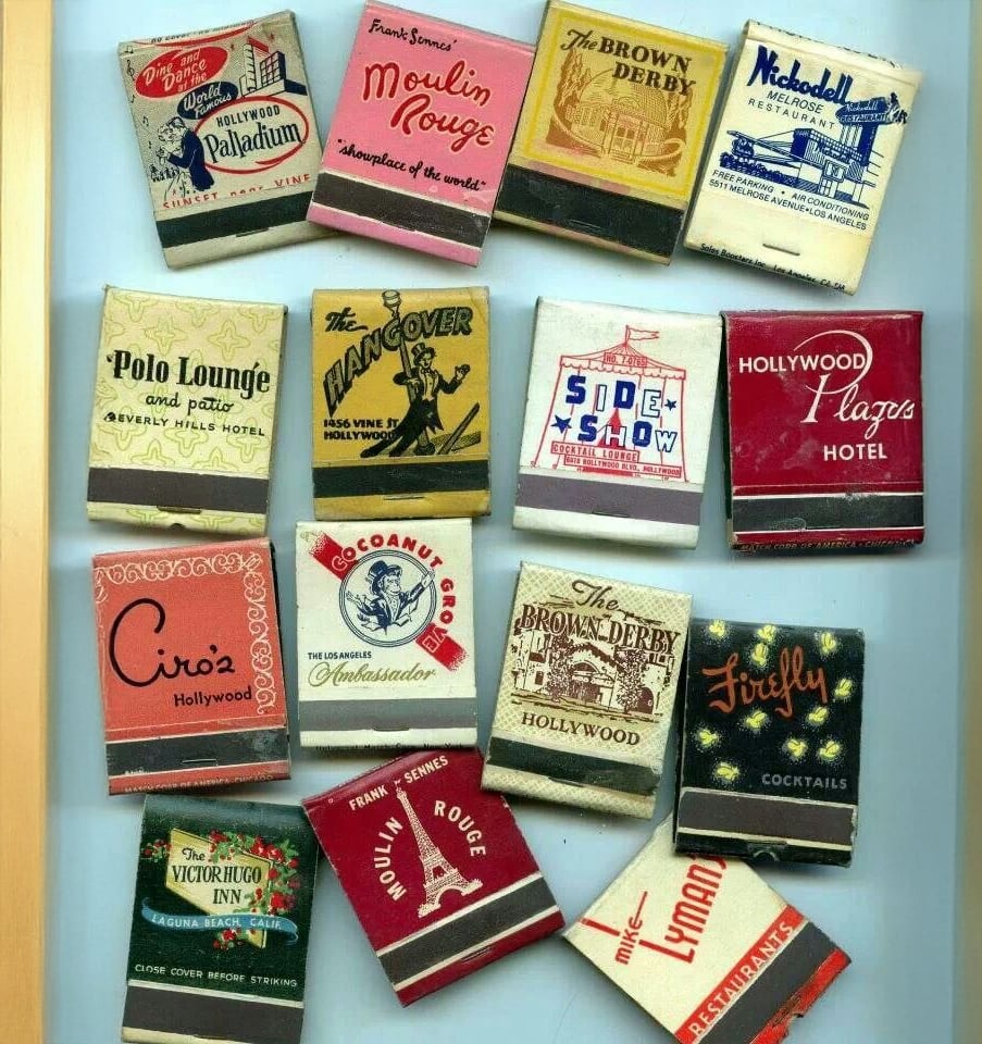 A collection of vintage matchbooks from various Hollywood hotels, lounges, and restaurants, arranged in three rows on a flat surface. Each matchbook has unique and colorful designs.