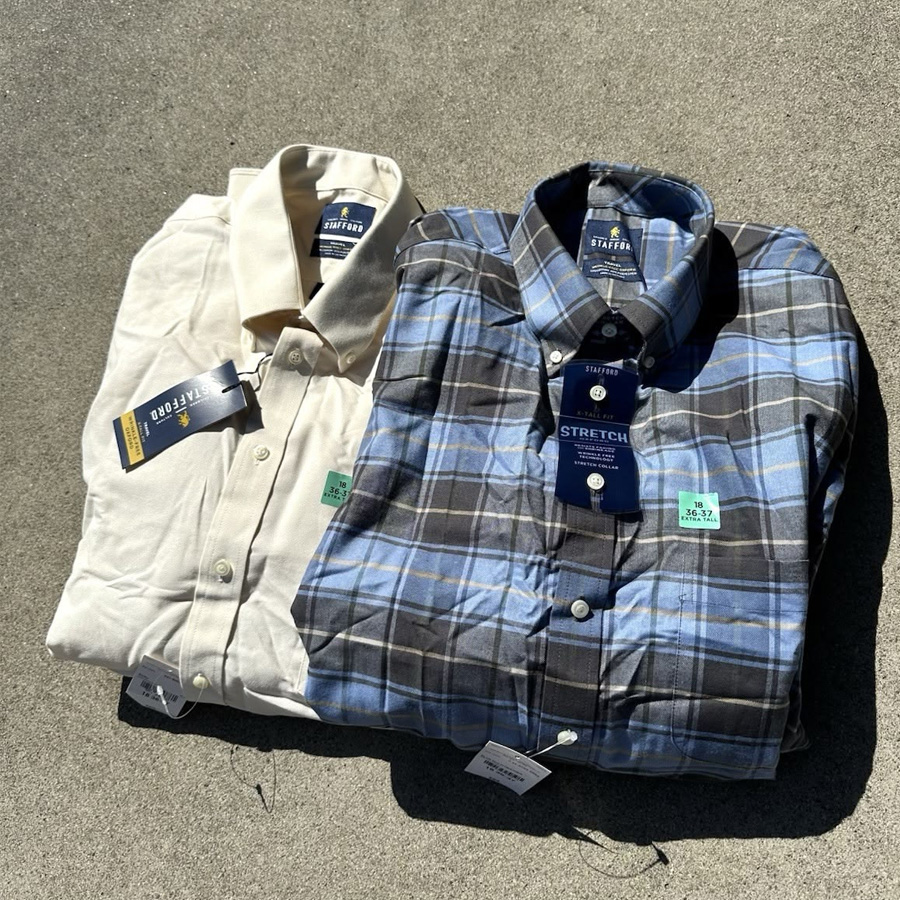 Two folded button-down shirts on a flat surface: one is solid beige, and the other is blue and gray plaid. Both have tags attached and are displayed in bright sunlight.