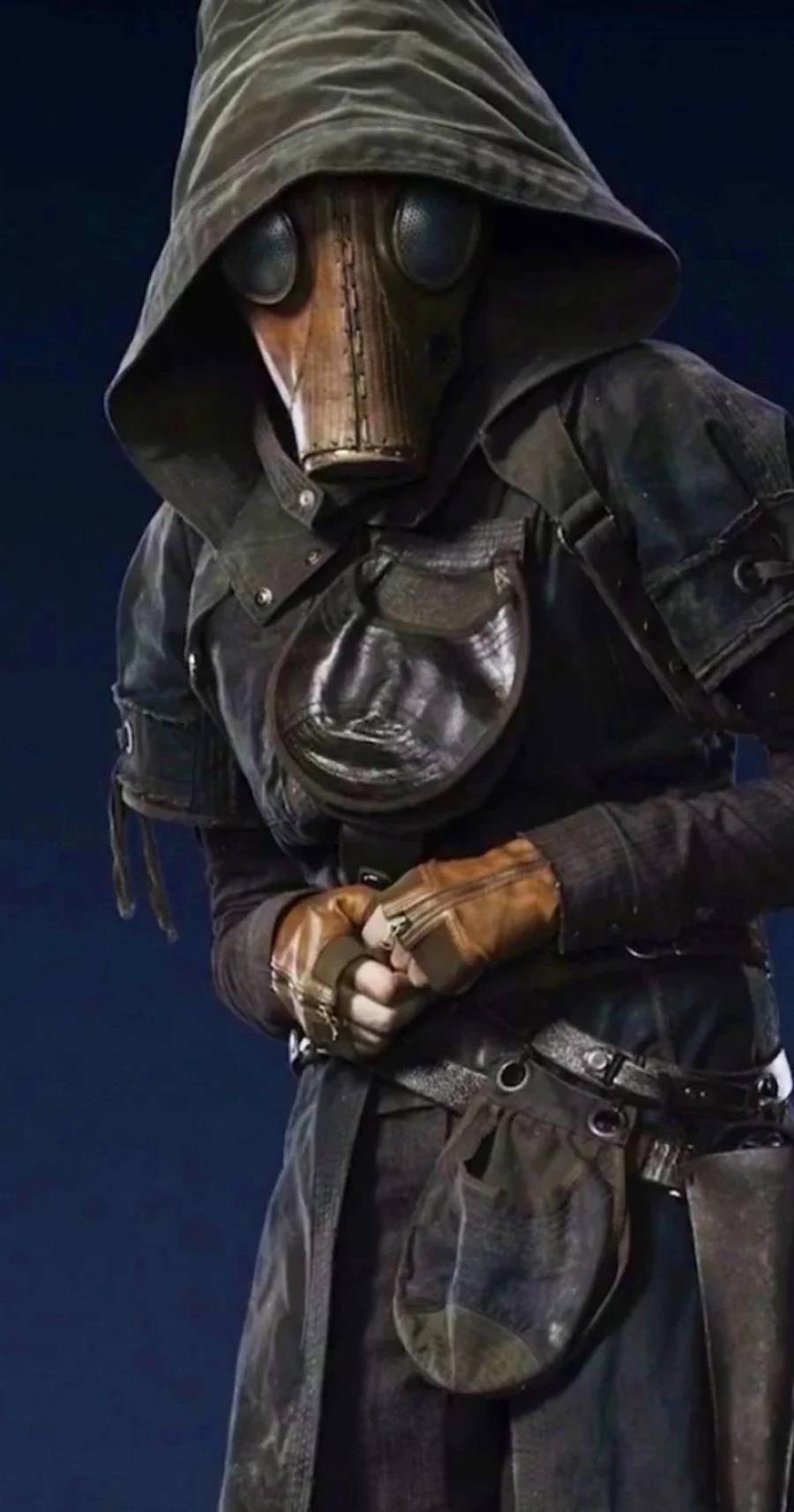 A person dressed in a dark, hooded cloak and leather gloves wears a vintage plague doctor mask with round eye lenses and a beak, standing against a dark background.