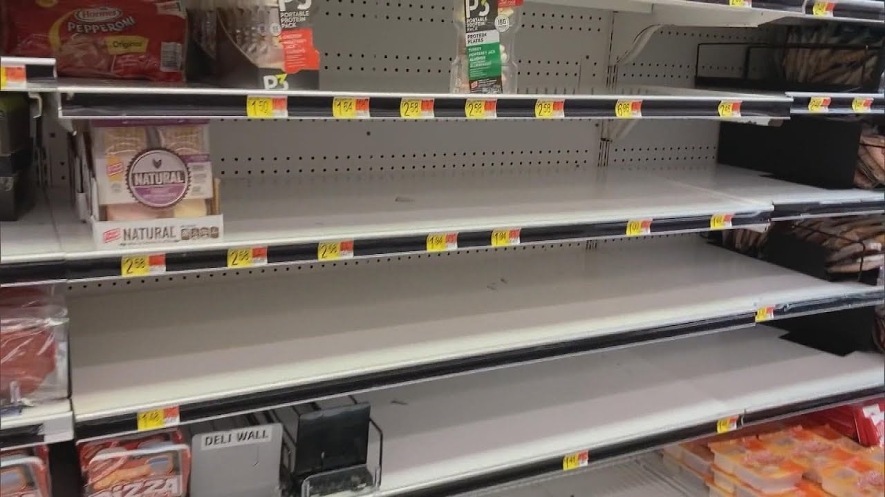 Nearly empty grocery store shelves with only a few remaining food items, including packaged meats and cheese, and mostly bare rows, suggesting a shortage or high demand for products.