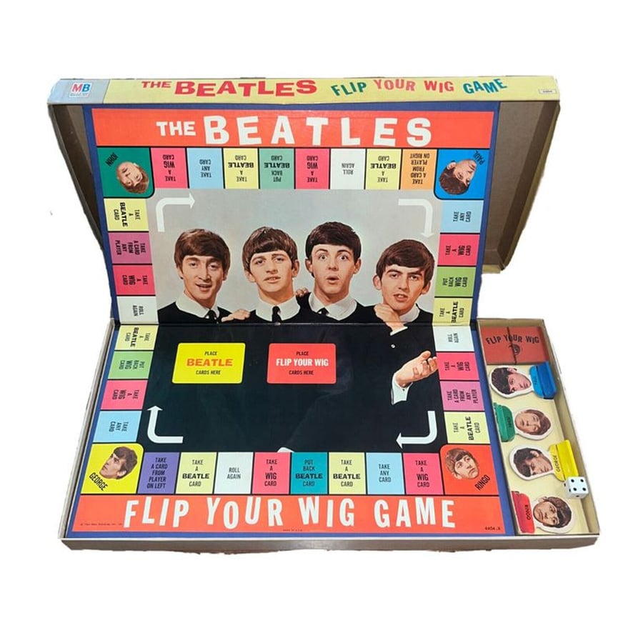 Open Beatles-themed board game called "Flip Your Wig," featuring band member images, colorful cards, dice, and playing pieces arranged inside the box. The board displays photos of the four band members.