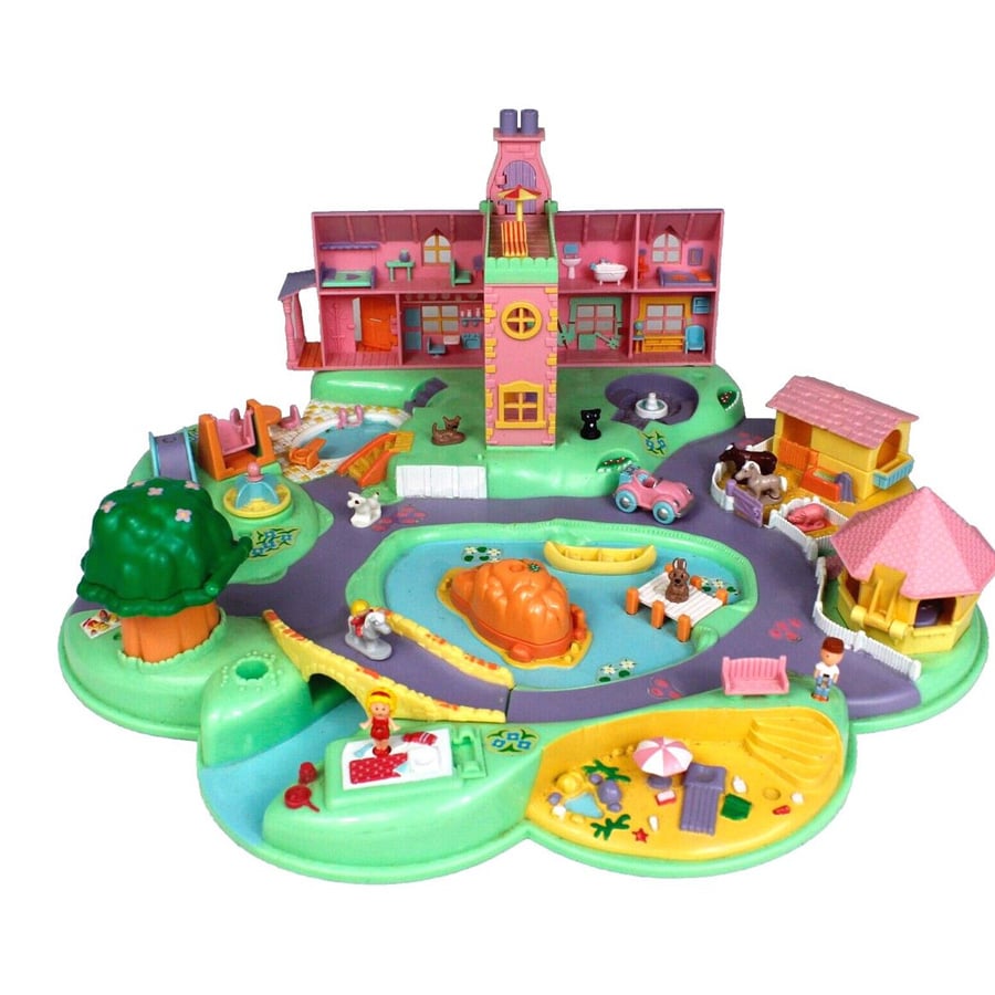 Colorful toy playset with a house, winding roads, small figures, animals, trees, a pond, playground, and various outdoor areas arranged in a circular layout.