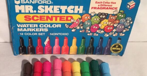 A box of Mr. Sketch scented markers with eight colorful markers in front. The box shows cartoon fruits and says each color has a different fragrance.