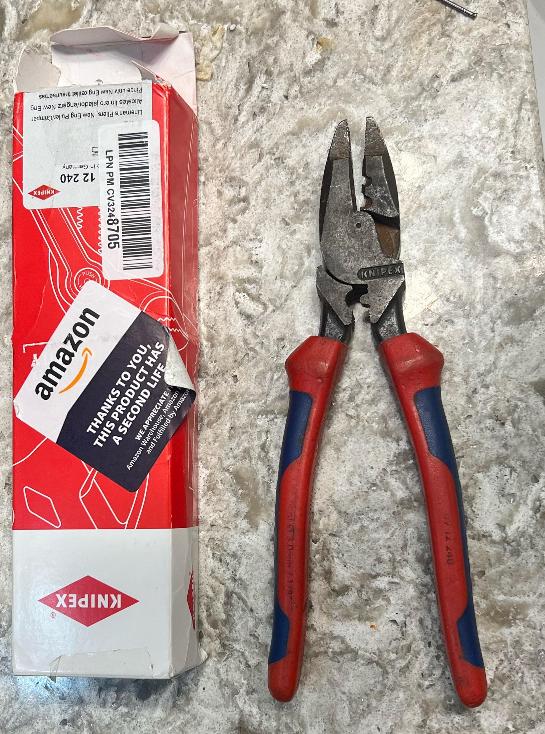 A pair of red and blue Knipex pliers lies on a countertop next to an opened Knipex box and an Amazon card.