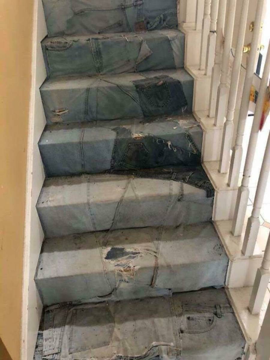 A staircase covered in old, worn denim jeans, with pockets and waistbands visible on each step, instead of traditional carpeting or finish.