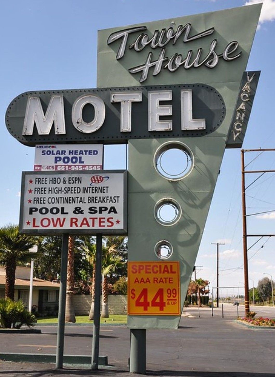 Retro roadside sign for Town House Motel advertising low rates, pool, free HBO, internet, breakfast, and a special AAA rate of $44.99. The sign has a vintage design with large letters and neon accents.