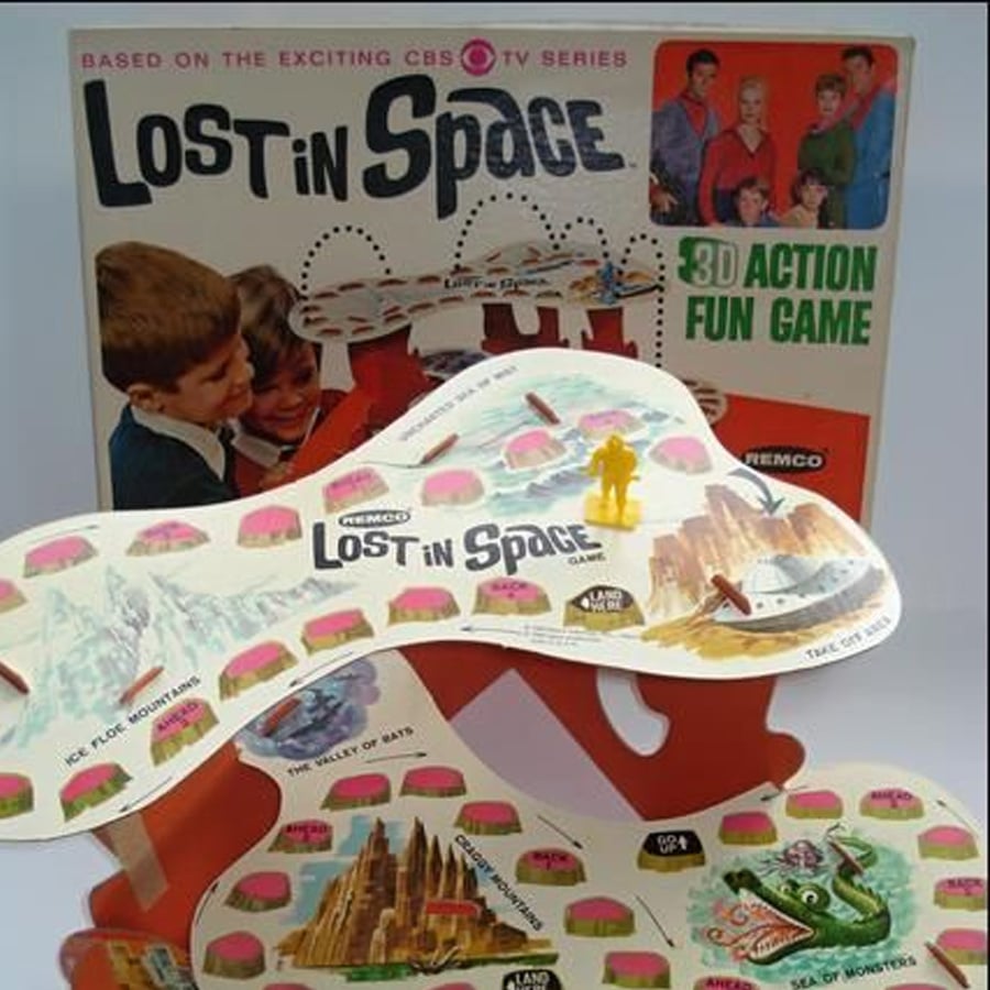 Vintage "Lost in Space" 3D board game with colorful paths, a yellow playing piece, and a box featuring the show's cast. The board stands elevated with various themed locations.