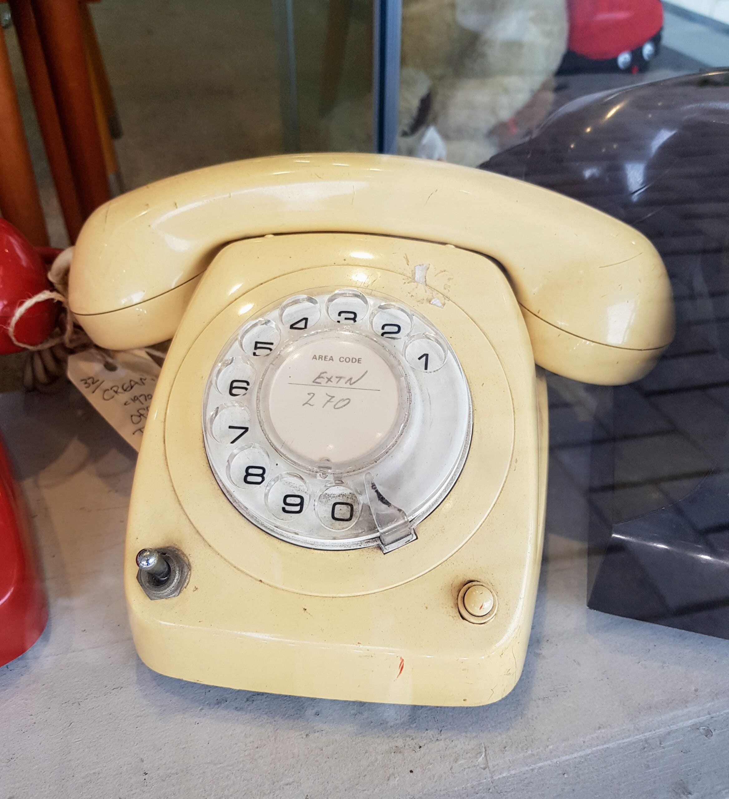 A vintage cream-colored rotary dial telephone sits on a gray surface, with a handwritten label reading "Extn 270" in the center of the dial.