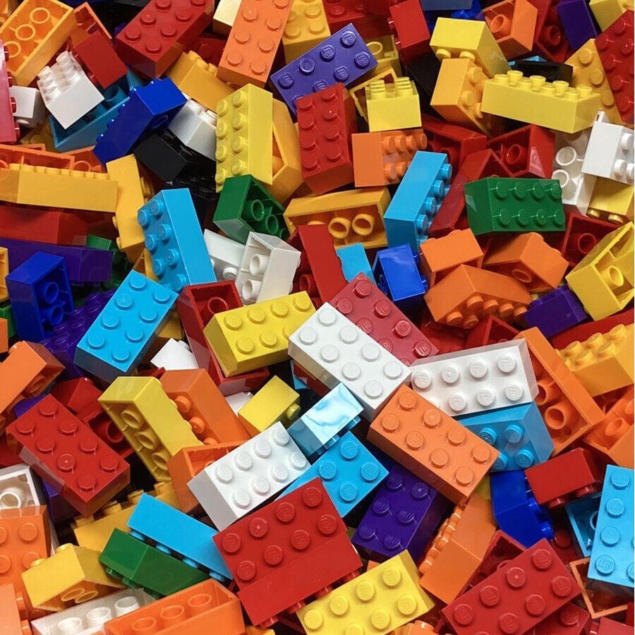 A pile of colorful LEGO bricks in various sizes and shapes, including red, blue, yellow, orange, white, green, and black pieces, scattered randomly across the image.