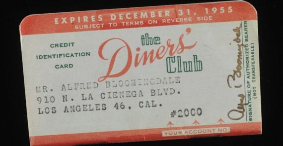 A vintage Diners’ Club credit card from 1955, issued to Alfred Bloomingdale, featuring a red and white design, member details, and a visible signature.