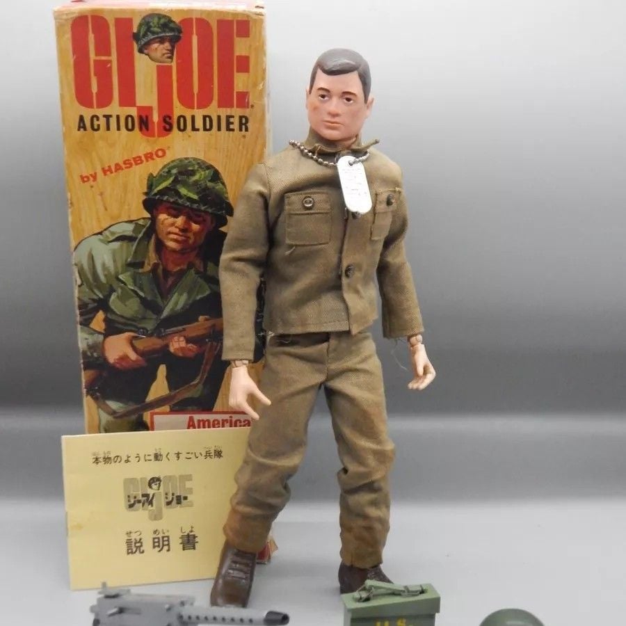 Vintage G.I. Joe action figure in brown uniform stands with accessories and original box featuring soldier artwork in the background.