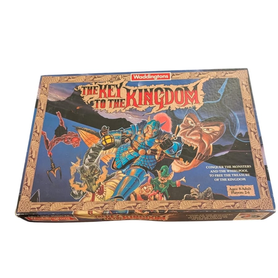 Box of "The Key to the Kingdom" board game showing a warrior, monsters, a dragon, and a large key, with ornate borders and fantasy artwork. Text describes the game for 2–6 players, ages 8 to adult.