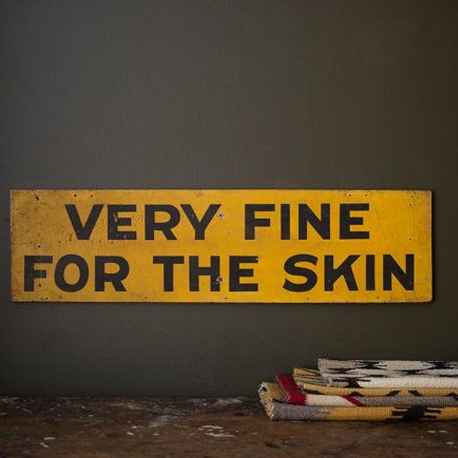 A yellow rectangular sign with bold black letters reads, "VERY FINE FOR THE SKIN." A folded patterned fabric lies partially visible at the bottom right.
