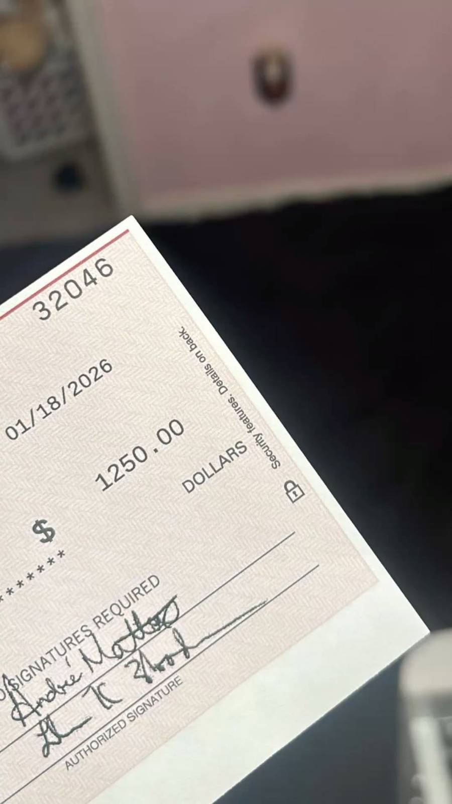 A close-up of a check dated 01/18/2026 for $1,250.00, showing signatures at the bottom and part of a dark background.