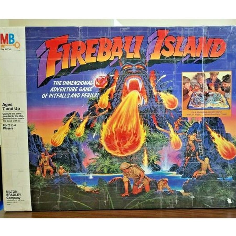 Fireball Island board game box featuring a volcano spewing fireballs at explorers. Includes tagline and a photo of children playing the game. For ages 7 and up, 2 to 4 players by Milton Bradley Company.
