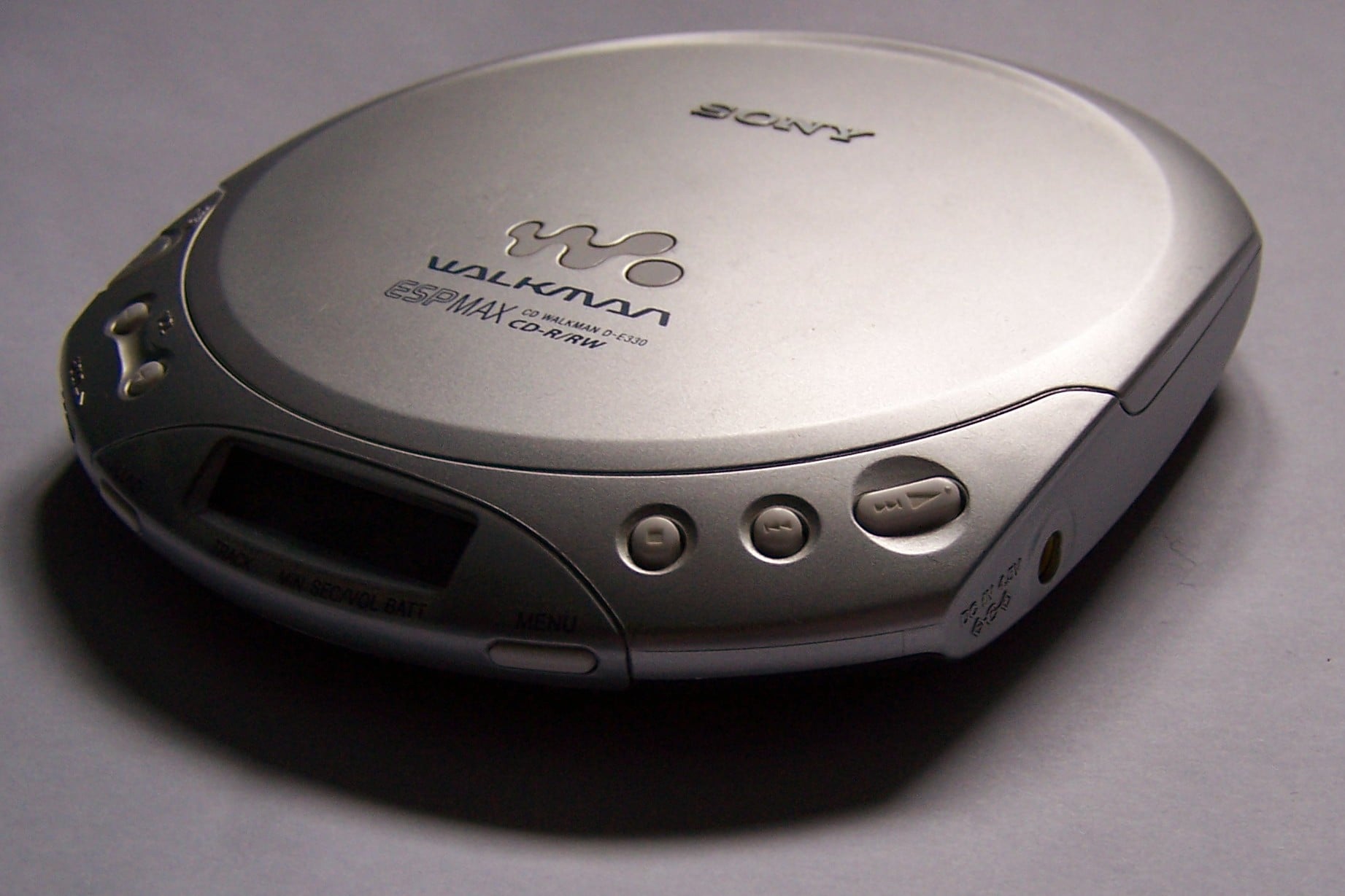 A silver Sony Walkman portable CD player on a plain surface, showing buttons, a display screen, and "Walkman" branding on the lid.