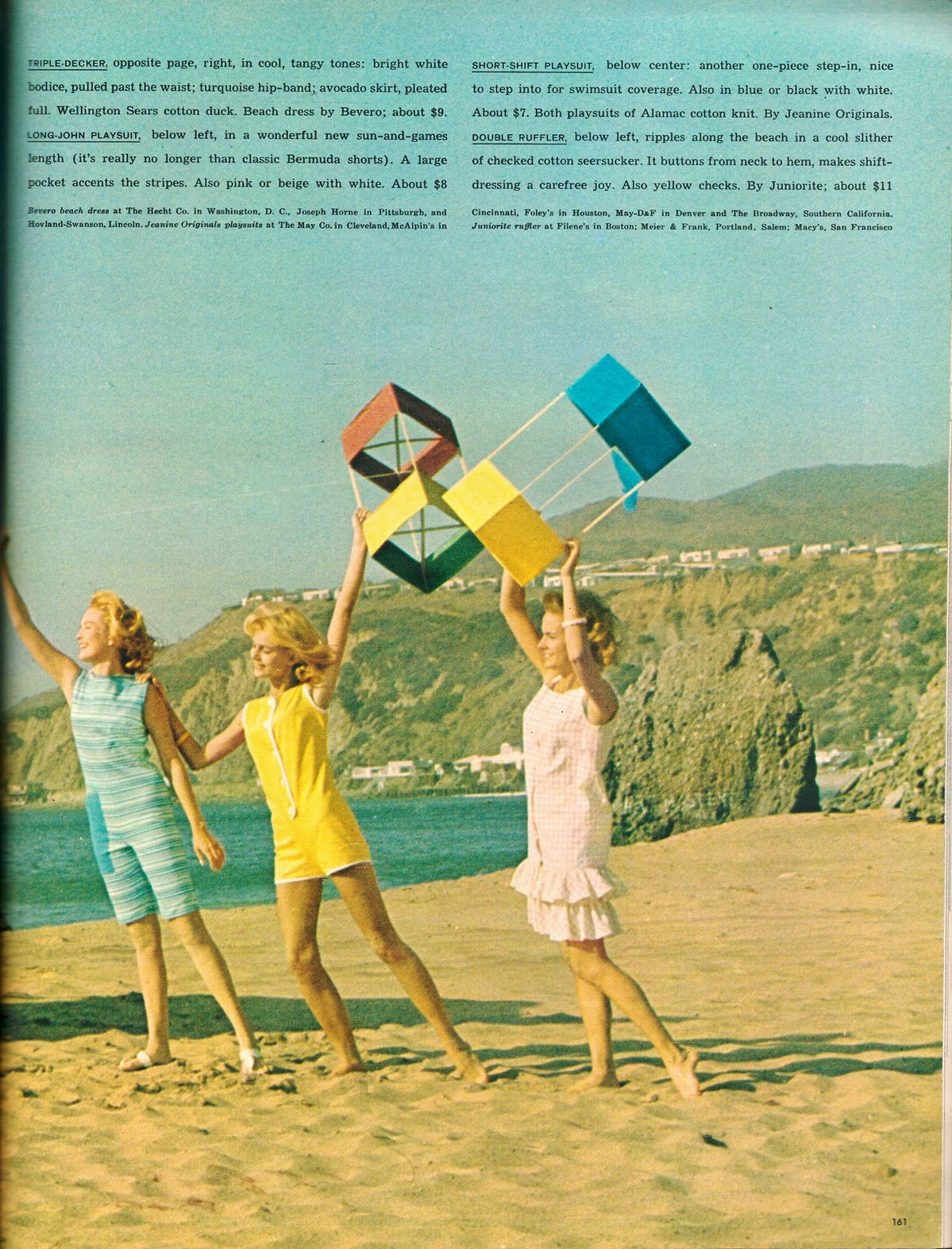 Three women in colorful retro swimsuits walk and run on the beach, laughing. Two hold geometric kites with the ocean and cliffs in the background under a blue sky. The scene is bright, warm, and lively.