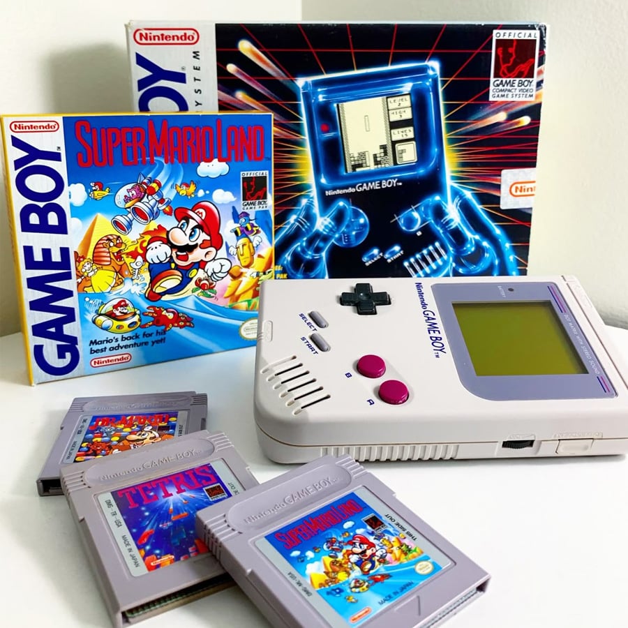 A classic Nintendo Game Boy with cartridges for Tetris, Super Mario Land, and Spider-Man, shown with their boxes and packaging in the background.