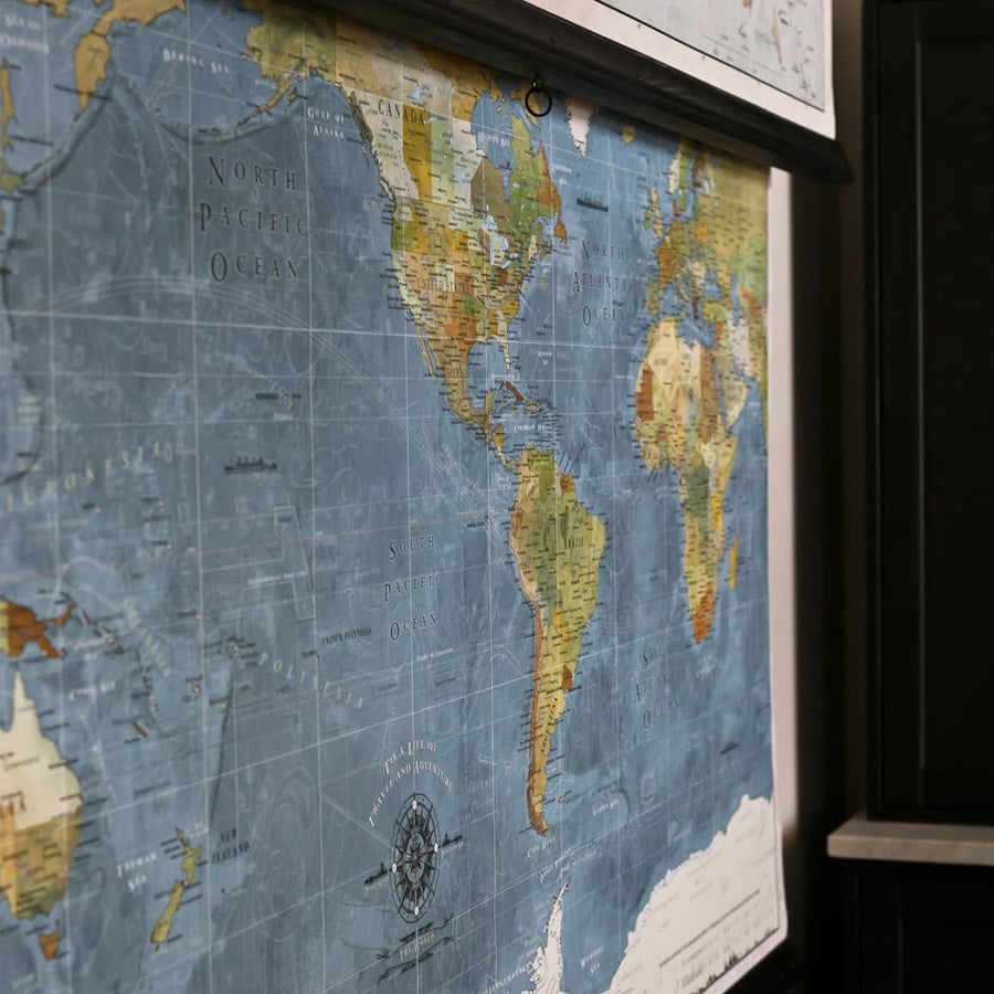 A close-up of a blue-toned world map showing parts of North and South America, Europe, and Africa, with ocean names and a decorative compass rose.