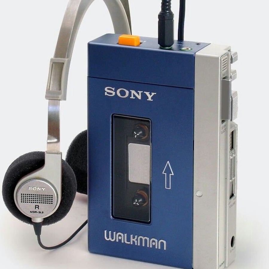 A blue Sony Walkman cassette player with attached silver headphones, showing a cassette tape inside and several control buttons on the top and side.