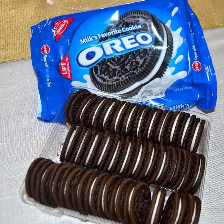 An open pack of Oreo cookies with two rows of chocolate sandwich cookies filled with white cream, and the blue Oreo packaging in the background.