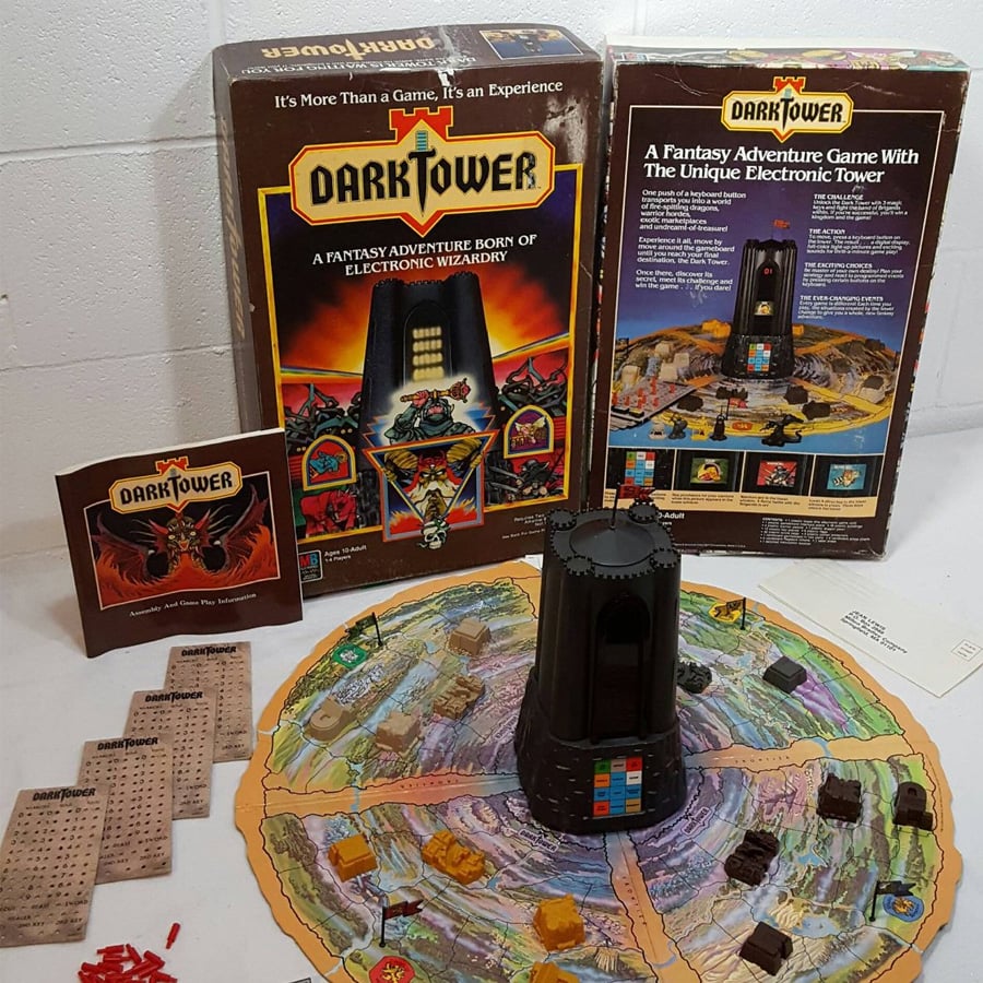 The Dark Tower board game set: box, game manual, cards, playing pieces, and an electronic tower, all arranged on the colorful circular game board.