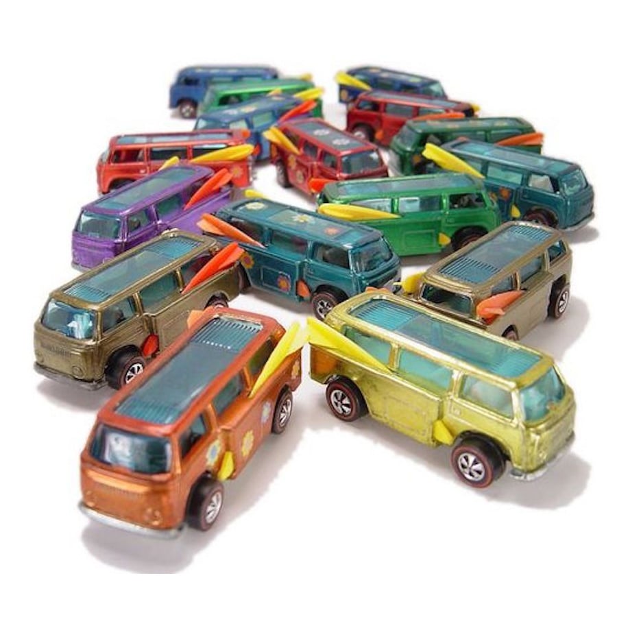 A group of colorful toy vans with surfboards on their roofs are arranged closely together on a white surface.