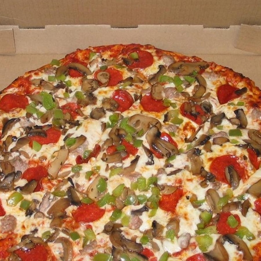 A pizza in an open box topped with pepperoni, sausage, mushrooms, green bell peppers, and melted cheese.