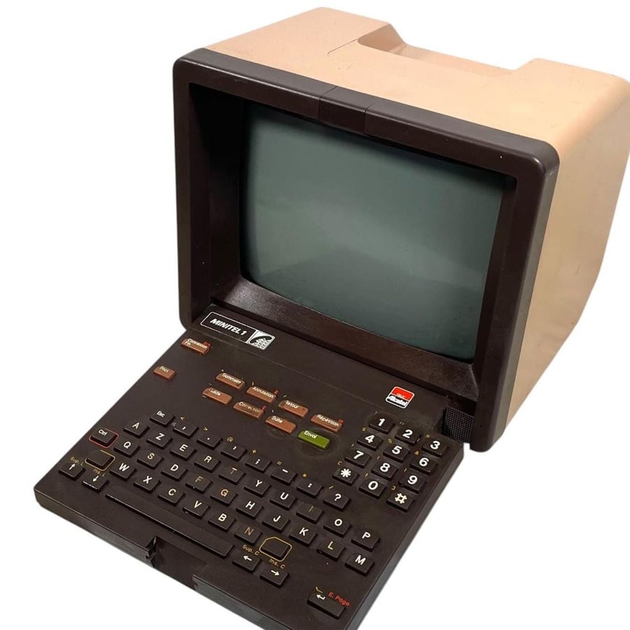 A vintage Minitel terminal with a small CRT screen and built-in keyboard. The device has a beige and black color scheme and is angled to the right.