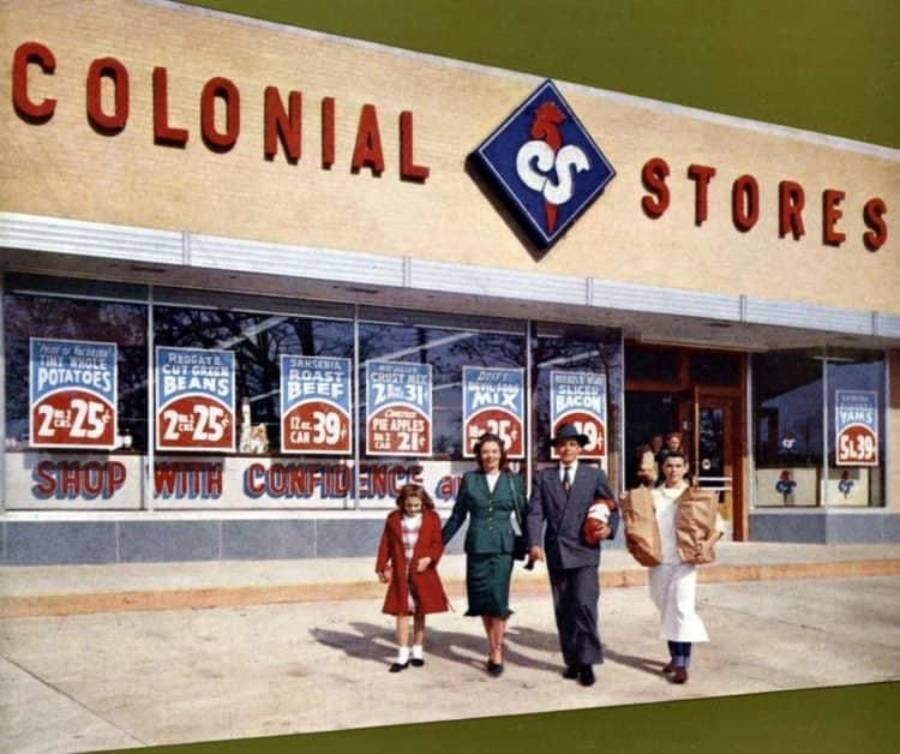 A family of four, two adults and two children, walk out of a Colonial Stores grocery store carrying bags, with large signs for various grocery deals visible in the store windows behind them.