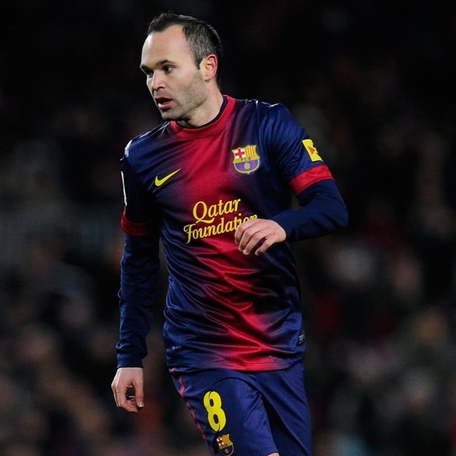 A soccer player in a blue and red FC Barcelona jersey with number 8 runs on the field during a match.