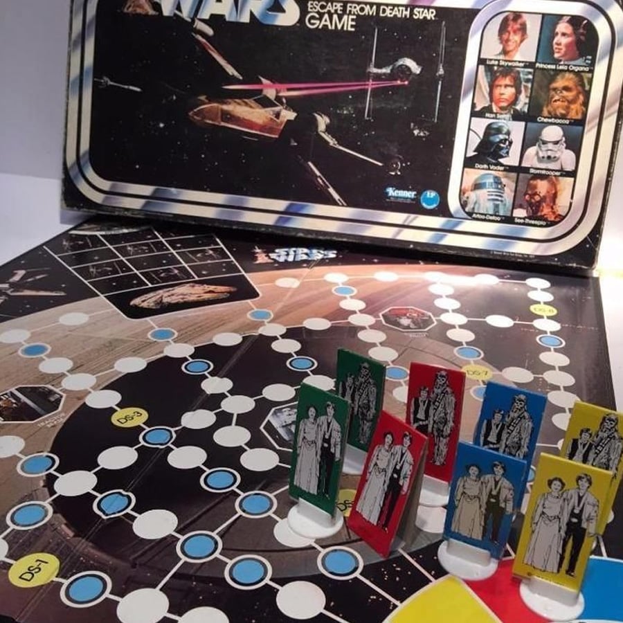 Star Wars Escape from Death Star board game with illustrated character tokens, a game board featuring paths and labeled spaces, and the game box showing spaceships and character images.