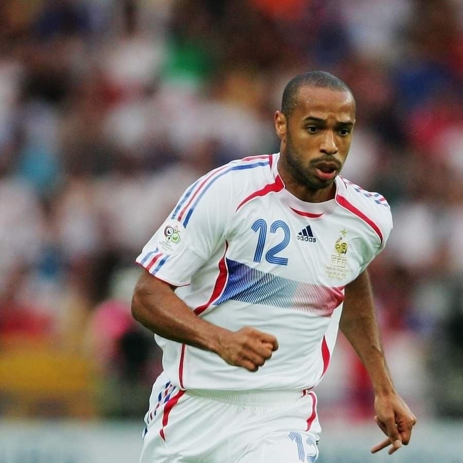 A male soccer player in a white France jersey with blue and red stripes, number 12, is running on the field during a game. The background shows a blurred crowd.