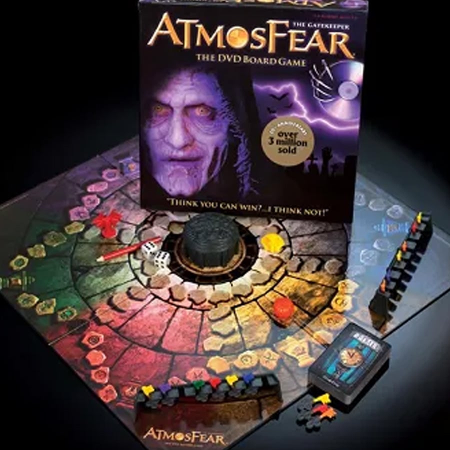 Atmosfear: The Gatekeeper DVD board game with colorful hexagonal game board, playing pieces, cards, dice, a well in the center, and the game box featuring a sinister face with purple hues and the game's title at the top.